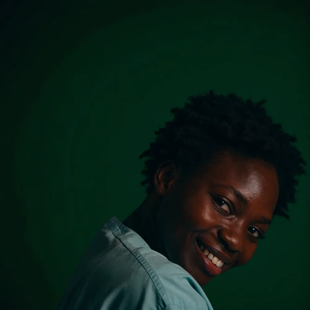 A nurse smiling against a deep green background
