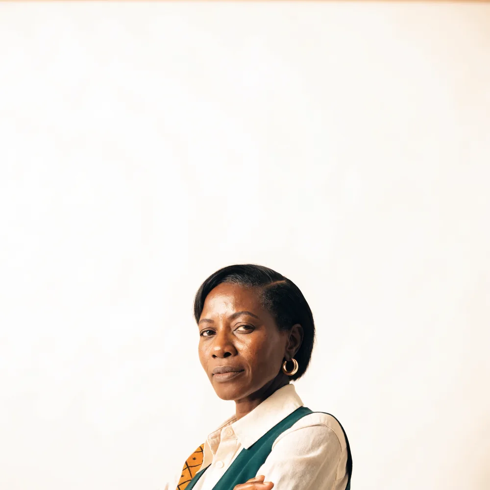 A business owner standing with her arms folded against a cream background