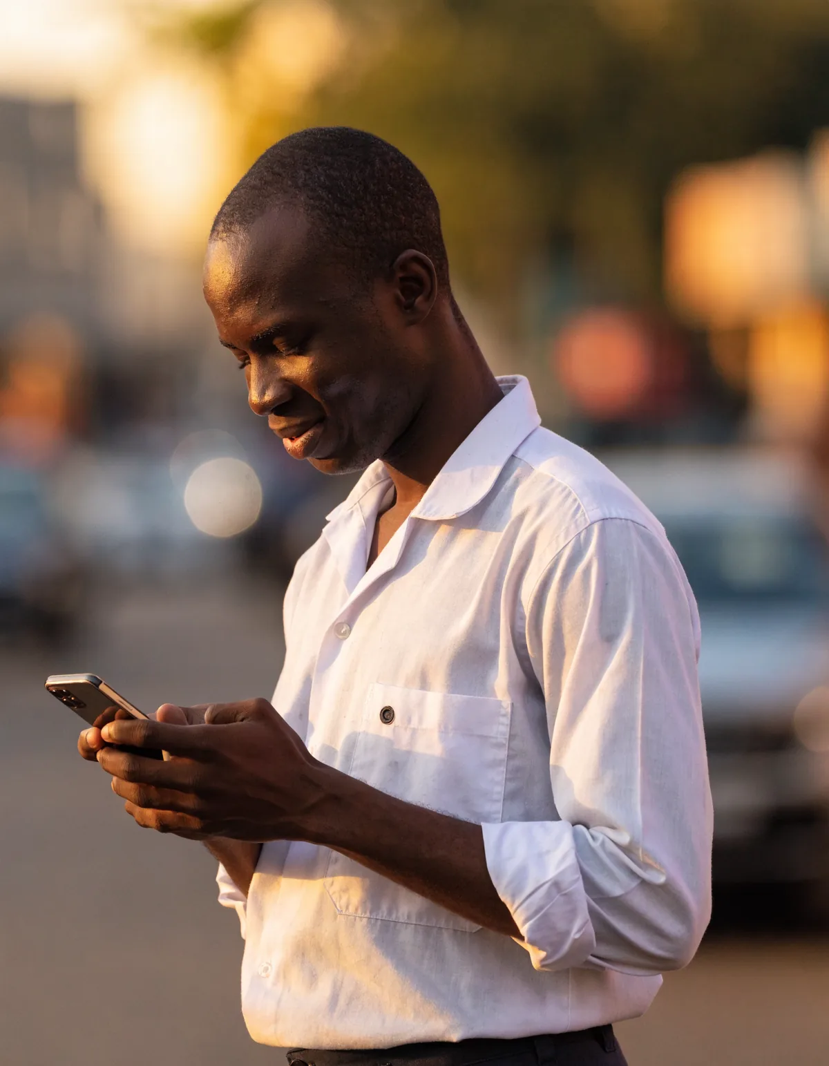 A man in Accra checking his phone in late afternoon light