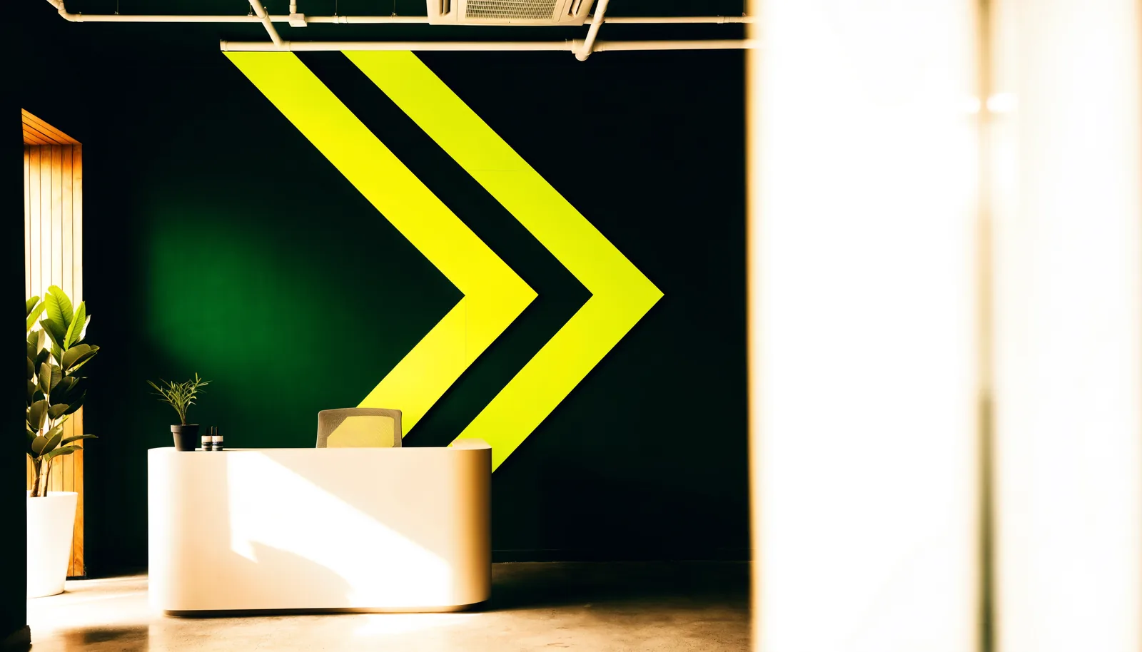 An office reception with a deep green feature wall carrying the volt chevron mark