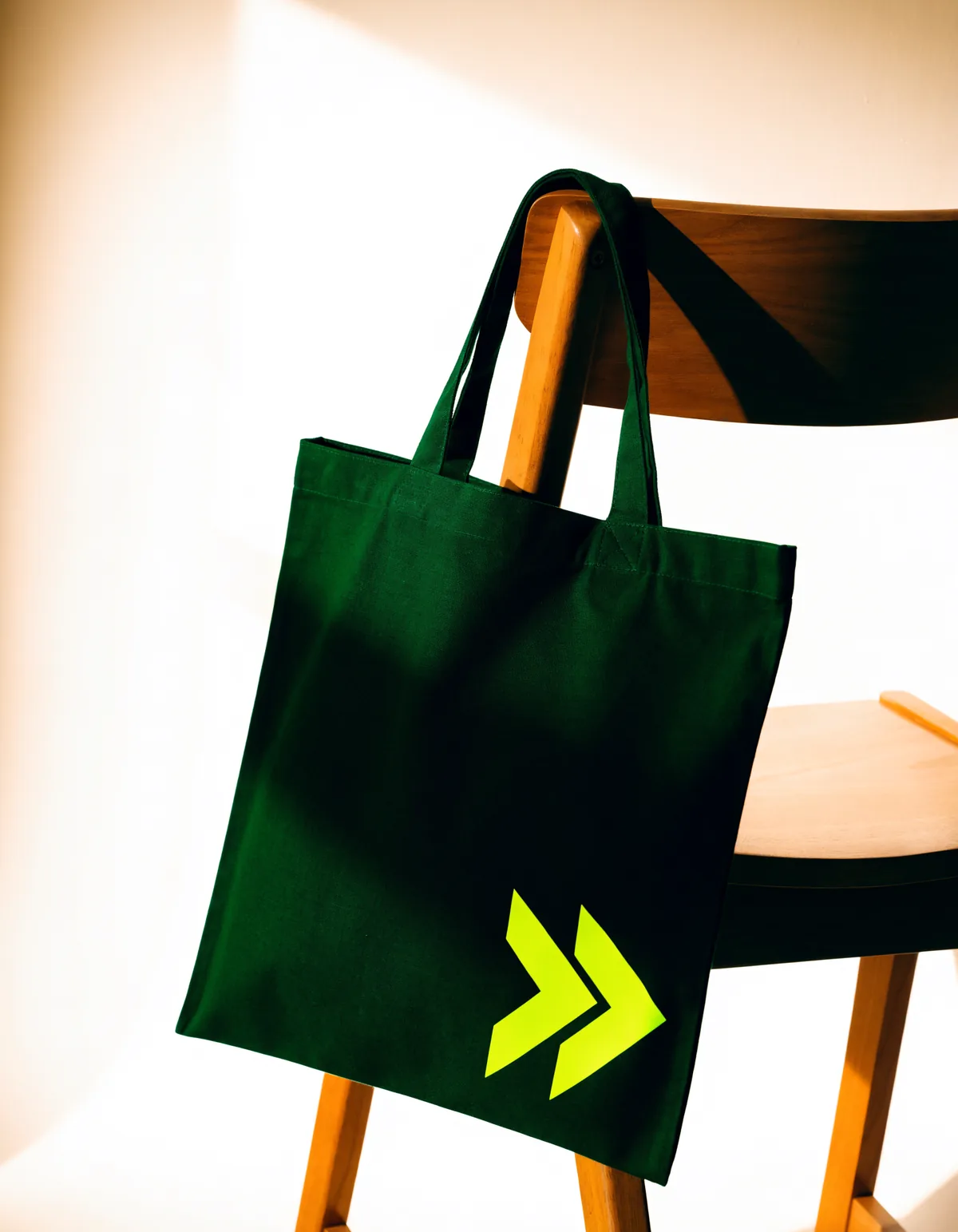 A deep green tote bag with the volt chevron mark on a wooden chair